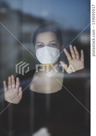 A woman staying at home in quarantine and watching the outside world through the window A woman staying at home in quarantine and watching the outside world through the window 139095017