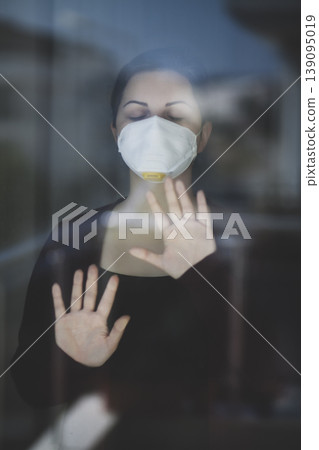 A woman staying at home in quarantine and watching the outside world through the window A woman staying at home in quarantine and watching the outside world through the window 139095019