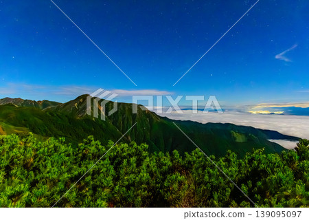 Night view from Mt. Chogatake in the Northern Alps: Mt. Jonen illuminated by moonlight and the lights of Nagano city. 139095097