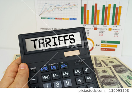 On the table there are financial reports, dollars, in the hands of a calculator with the inscription - Tariffs On the table there are financial reports, dollars, in the hands of a calculator with the inscription - Tariffs 139095308