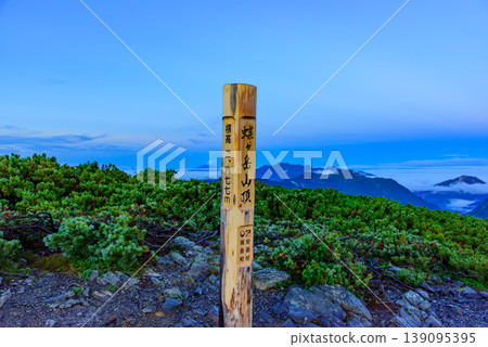 A spectacular panoramic view from the summit of Mt. Chogatake in the Northern Alps, with the summit marker and distant views of Mt. Norikura and Mt. Ontake. A spectacular panoramic view from the summit of Mt. Chogatake in the Northern Alps, with the summit marker and distant views of Mt. Norikura and Mt. Ontake. 139095395