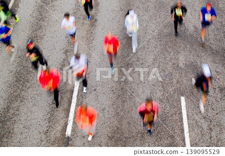 Aerial overhead view of crowd of runners with motion blur competing in urban city marathon race event 139095529