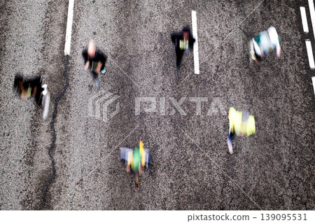 Aerial view of runners with motion blur competing in city marathon race event Aerial view of runners with motion blur competing in city marathon race event 139095531