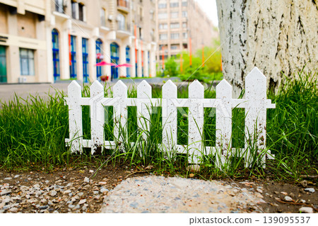 Classic white wooden picket fence with green grass and bushes in residential neighborhood Classic white wooden picket fence with green grass and bushes in residential neighborhood 139095537