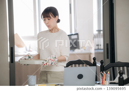Serious asian woman holding tray working an online business studying technology at home Serious asian woman holding tray working an online business studying technology at home 139095695