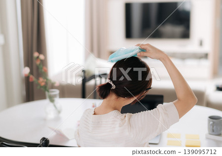 Exhausted asian woman feeling sick and stressed with terrible headache putting an ice pack on head while working online business and studying at home using modern technology to finish tasks Exhausted asian woman feeling sick and stressed with terrible headache putting an ice pack on head while working online business and studying at home using modern technology to finish tasks 139095712