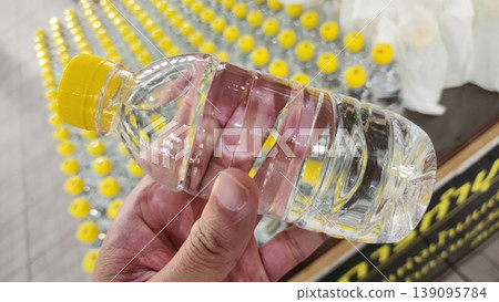 Person Holding a Clear Plastic Mineral Water Bottle with a Bright Yellow Cap Person Holding a Clear Plastic Mineral Water Bottle with a Bright Yellow Cap 139095784