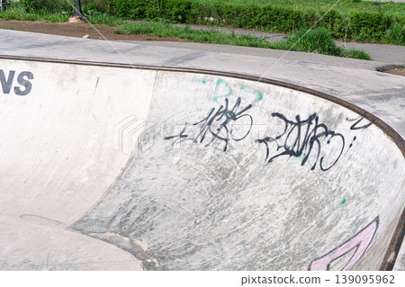 Empty concrete skatepark ramp with black graffiti tags Empty concrete skatepark ramp with black graffiti tags 139095962