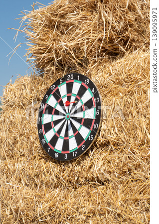 A dartboard with a red dart in the bullseye on a haystack A dartboard with a red dart in the bullseye on a haystack 139095971
