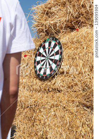 A person in a white shirt playing darts on a haystack target 139095984