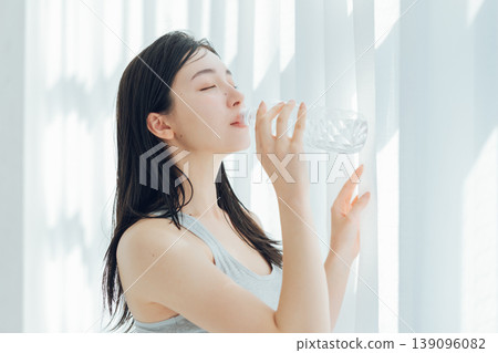 A woman drinking water at the window A woman drinking water at the window 139096082