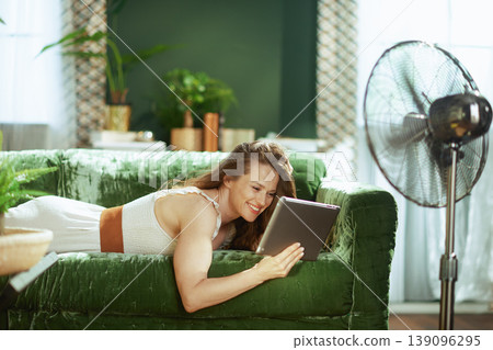 Relaxed Woman Browsing Tablet on Green Velvet Sofa 139096295