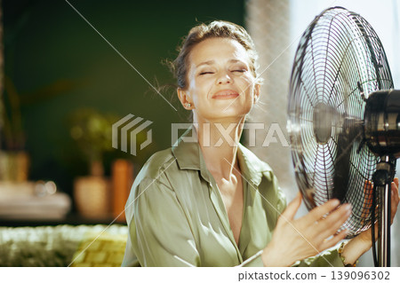 Close-up of Woman Enjoying Cool Air from Fan 139096302