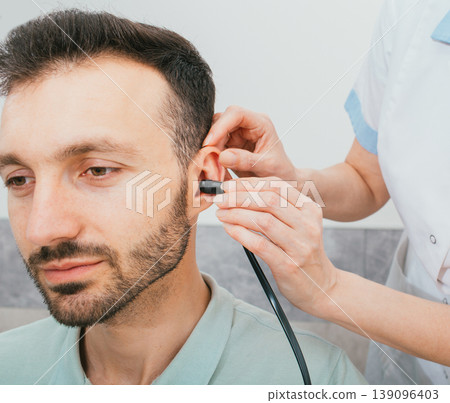 Mixed race man having a hearing test with special medical equipment. Impedance audiometry, tympanometry in a hearing center 139096403
