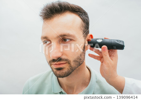Male patient receives ear examinations. Video otoscopy procedure, close-up. Hearing clinic Male patient receives ear examinations. Video otoscopy procedure, close-up. Hearing clinic 139096414