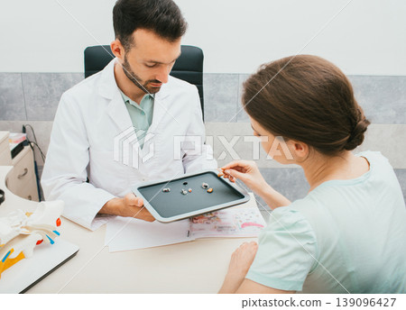 Hearing solution for adults. Audiologist selecting a hearing aid for a caucasian woman. Patient needs good hearing aids so that she can hear the sounds of the world. Hearing solution for adults. Audiologist selecting a hearing aid for a caucasian woman. Patient needs good hearing aids so that she can hear the sounds of the world. 139096427