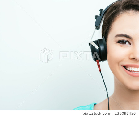 Mixed race woman with toothy smile getting a hearing test, audiometer hearing test. Half face, on gray background 139096456