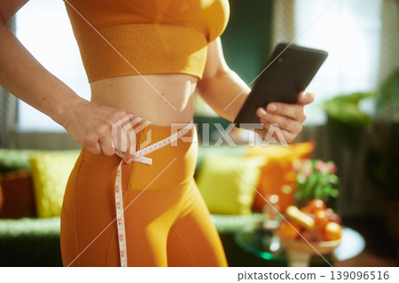 Digital Wellness Tracking: Woman Using Phone and Tape Measure 139096516
