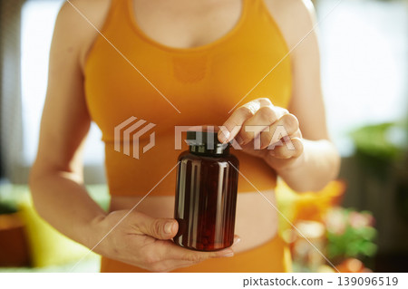 Woman with Supplement Bottle in Mustard Yellow Activewear Woman with Supplement Bottle in Mustard Yellow Activewear 139096519
