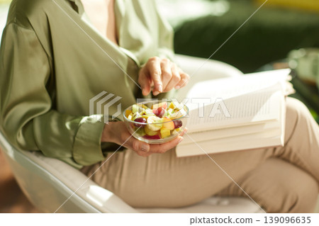 Relaxed Woman Reading with a Bowl of Fresh Fruit Relaxed Woman Reading with a Bowl of Fresh Fruit 139096635