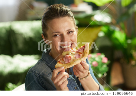 Smiling Woman Holding Pizza in Living Room 139096646
