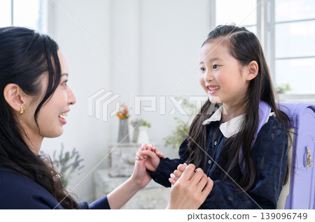 A Japanese parent and child talking while the child is wearing a school backpack. 139096749