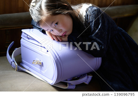 A Japanese girl sitting on a sofa, leaning against her schoolbag. A Japanese girl sitting on a sofa, leaning against her schoolbag. 139096795