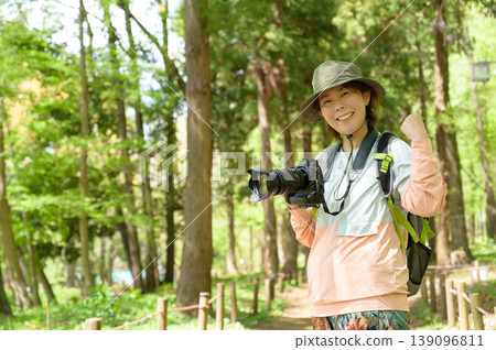 Japanese woman strikes a triumphant pose with a camera in the mountains Japanese woman strikes a triumphant pose with a camera in the mountains 139096811