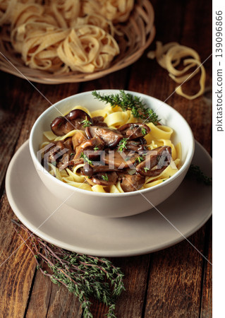Noodles with mushrooms and thyme on a rustic wooden table. 139096866