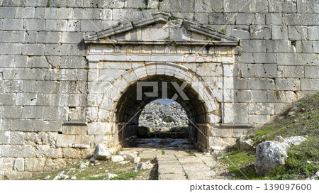 Ancient stone gateway at Letoon sanctuary, featuring arched entrance, weathered walls and pathway leading into historic Lycian ruins near city of Xanthos, Mugla, Turkey Ancient stone gateway at Letoon sanctuary, featuring arched entrance, weathered walls and pathway leading into historic Lycian ruins near city of Xanthos, Mugla, Turkey 139097600