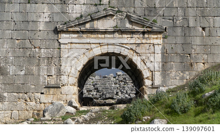 Ancient arched stone entrance at Letoon Sacred Area ruins in Mugla, Turkey. Historical Lycian architecture under a blue sky. 139097601