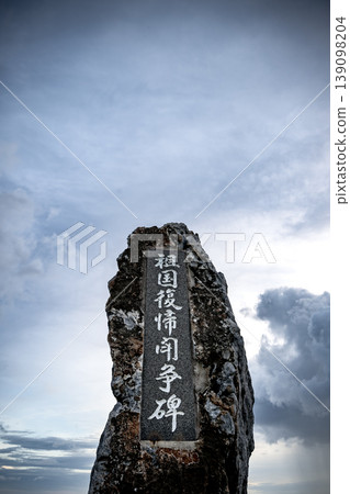 The monument commemorating the struggle for the return to Japan stands tall against the cloudy sky at Cape Hedo. The monument commemorating the struggle for the return to Japan stands tall against the cloudy sky at Cape Hedo. 139098204
