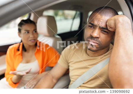 Black couple arguing in car, frustrated man resting head on fist Black couple arguing in car, frustrated man resting head on fist 139098692