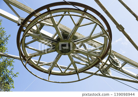 Weathered industrial pulley wheel against a clear blue sky Weathered industrial pulley wheel against a clear blue sky 139098944
