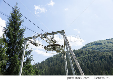 Chairlift pulley system against clear summer sky in mountainous forest 139098960