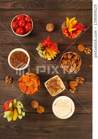 Oriental cuisine and healthy snack concept, Healthy food kitchen background with hummus bowl and raw vegetable sticks, nuts and dried apricots. Hummus platter with appetizers, traditional vegan snacks Oriental cuisine and healthy snack concept, Healthy food kitchen background with hummus bowl and raw vegetable sticks, nuts and dried apricots. Hummus platter with appetizers, traditional vegan snacks 139099029