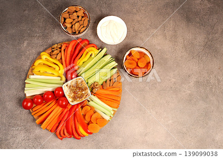 Healthy food kitchen background with hummus bowl and raw vegetable sticks, nuts and dried apricots. Hummus platter with appetizers, Middle Eastern plate, traditional vegan snacks, oriental cuisine 139099038