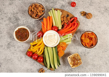 Hummus platter with appetizers, healthy food kitchen background with hummus bowl and raw vegetable sticks, nuts and dried apricots. Middle East plate, traditional vegan appetizers, Hummus platter with appetizers, healthy food kitchen background with hummus bowl and raw vegetable sticks, nuts and dried apricots. Middle East plate, traditional vegan appetizers, 139099041