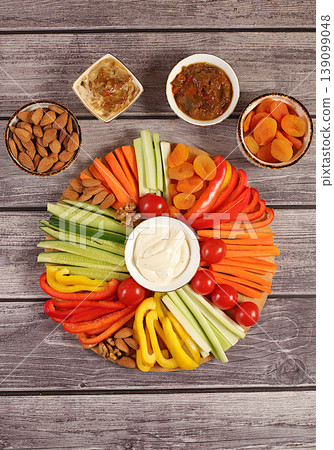 Hummus platter with appetizers, healthy food kitchen background with hummus bowl and raw vegetable sticks, nuts and dried apricots. Middle East plate, traditional vegan appetizers, Hummus platter with appetizers, healthy food kitchen background with hummus bowl and raw vegetable sticks, nuts and dried apricots. Middle East plate, traditional vegan appetizers, 139099048
