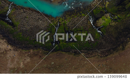 Aerial View of Turquoise River and Waterfalls in Iceland's Mossy Terrain 139099648