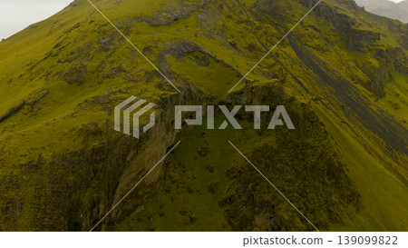 Aerial View of Moss Covered Volcanic Hillside with Steep Cliffs in Iceland Aerial View of Moss Covered Volcanic Hillside with Steep Cliffs in Iceland 139099822
