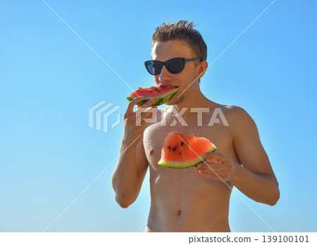 Man eating fresh watermelon slice on sunny summer day against blue sky Man eating fresh watermelon slice on sunny summer day against blue sky 139100101