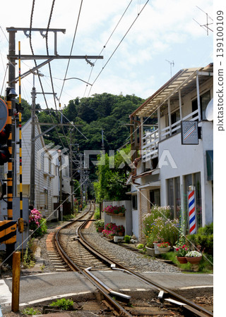 鎌倉江之電線鐵路道口的一幕:鐵軌穿過居民區,附近有一家復古理髮店。夏季。 鎌倉江之電線鐵路道口的一幕:鐵軌穿過居民區,附近有一家復古理髮店。夏季。 139100109