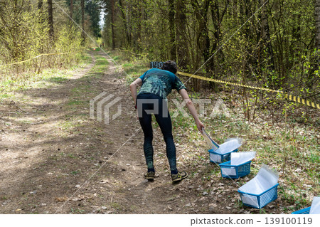 Orienteering participant selecting map from basket at start 139100119