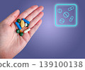 Hand holds pills capsules medicine vitamins supplements beside neon icon on blue medical background. Clean pharmacy scene for dosage planning, healthcare treatment, medication and wellness care. 139100138