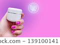 Manicure cosmetics cream skincare hand with pink nails holds natural beauty jar on purple background. Neon leaf icon suggests eco product, spa care, skin moisture, cuticle treatment and wellness care. 139100141