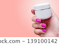 Manicure cosmetics cream skincare hand with pink nails holds white jar on pastel pink background for beauty care. Spa moisturizing product for skin, cuticle, body care, salon procedure and treatment. 139100142