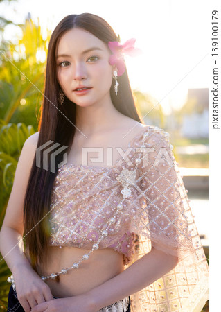 Trendy Thai fashion woman wearing a traditional Sabai paired with denim jeans at temple, reflecting the growing fashion trend in Thailand that blends cultural heritage with contemporary street style. 139100179