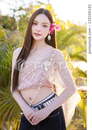 Trendy Thai fashion woman wearing a traditional Sabai paired with denim jeans at temple, reflecting the growing fashion trend in Thailand that blends cultural heritage with contemporary street style. 139100182
