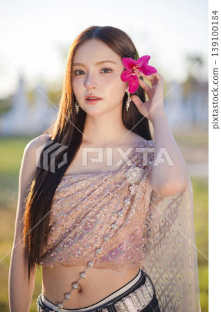 Trendy Thai fashion woman wearing a traditional Sabai paired with denim jeans at temple, reflecting the growing fashion trend in Thailand that blends cultural heritage with contemporary street style. 139100184